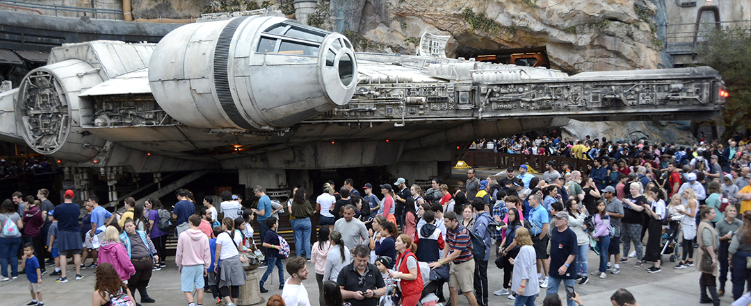A crowd moving past the Millennium Falcon at Disney's Galaxy's Edge.